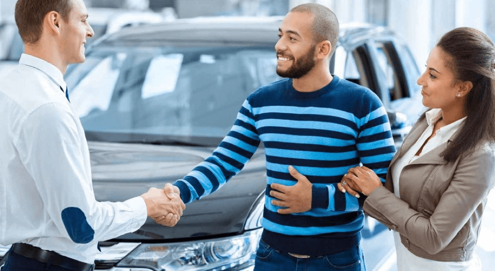 car dealer shaking hands with couple