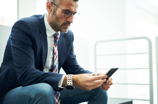 Confident male entrepreneur in trendy eyeglasses dialing number on smartphone for contact banking service, executive manager checking notification on mobile sitting near copy space for advertising Executive Video Conferencing